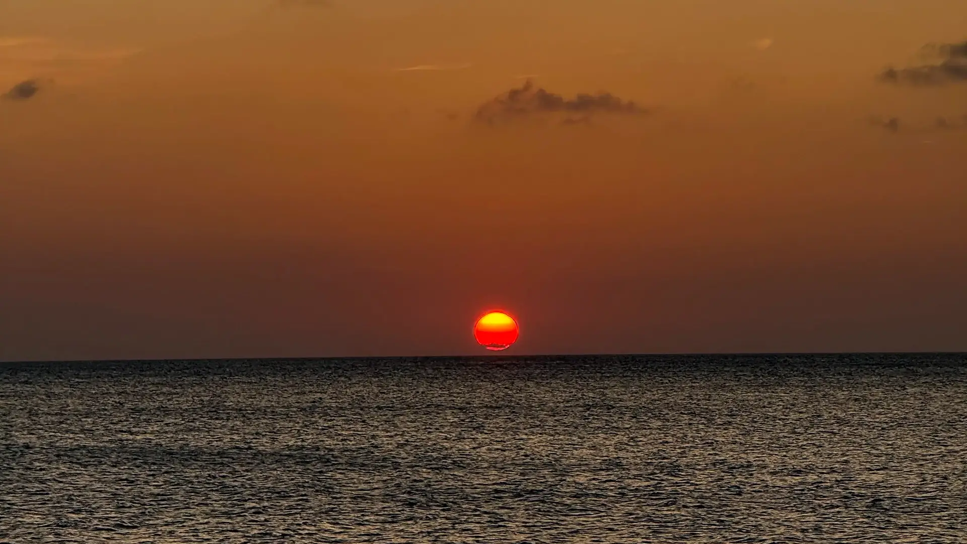Red sun setting over the Caribbean horizon